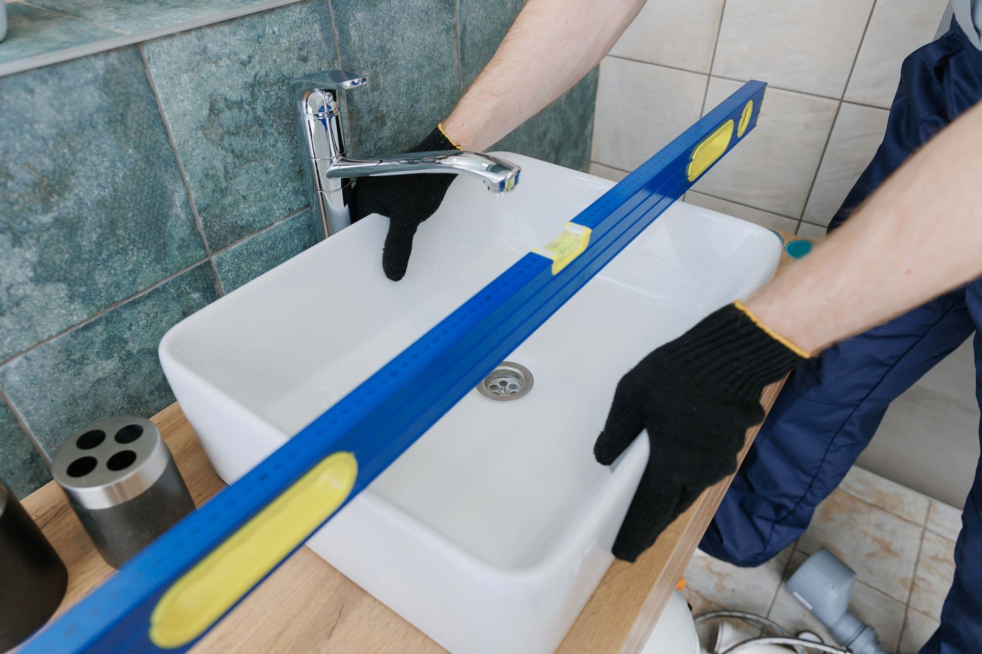 A fitter levelling a new basin with a spirit level